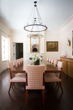 a dining room table with chairs and a chandelier hanging from it's ceiling