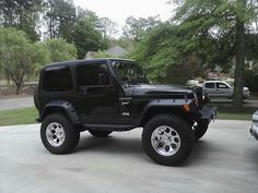 a black jeep is parked in a driveway