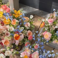 two vases filled with flowers sitting on top of a wooden floor next to each other