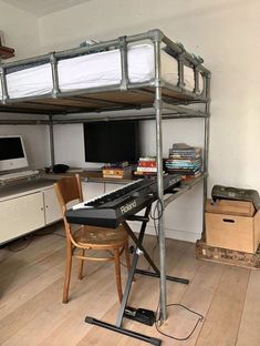 a room with a desk, keyboard and computer on the top bunk bed in it