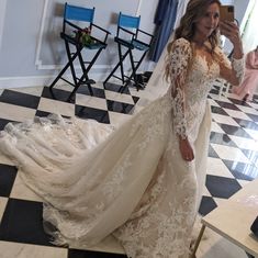 a woman in a wedding dress taking a selfie with her cell phone while standing on a checkered floor