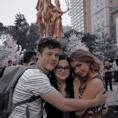 two people hugging each other in front of a statue