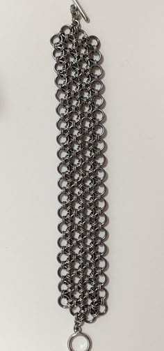 "This Japanese 12 in 1 chain maille bracelet is made with bright stainless steel and \"stormy\" grey anodized aluminum. Because of the mixture of materials it has a nice weight without being too heavy for a bracelet of this width. This is a great piece that can be dressed up or down for any occasion.  The bracelet measures 8.5 inches. If you need an adjustment please reach out to me and I will do my best to accommodate your request.  Most of my pieces are one of a kind, however, if you see a pat Chain Maille Patterns Tutorials, Chainmaille Jewelry Patterns, Chain Maille Patterns, Chain Maille Bracelet, Gothic Jewelry Diy, Chainmail Bracelet, Chainmail Jewelry, Chainmaille Bracelet, Chain Maille Jewelry