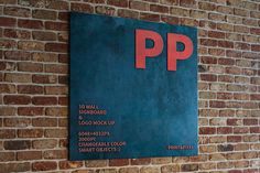 a sign on the side of a brick building that says pp and has red letters