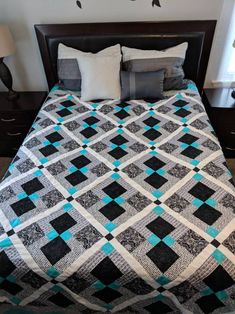 a black and white quilt on a bed in a room with two lamps next to it