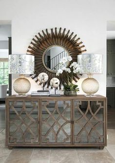 a room with a mirror, vases and other items on the sideboard in front of it