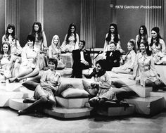 a group of women sitting on top of couches in front of a man and woman