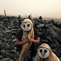 two people with owl masks on their heads and one holding an owl's head