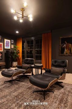 a living room with two chairs, a table and pictures on the wall behind them