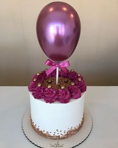 a white cake with purple flowers and a balloon on top