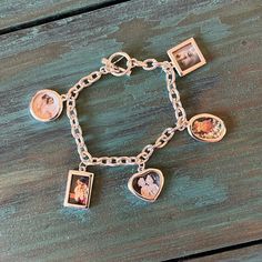 a bracelet with four pictures on it and two charms attached to the clasp, sitting on top of a wooden surface