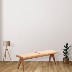 a wooden bench sitting on top of a hard wood floor next to a potted plant