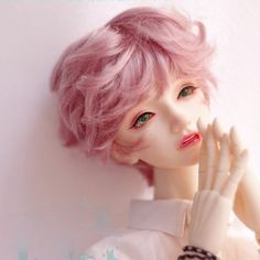 a close up of a doll with pink hair wearing a white dress and bracelets