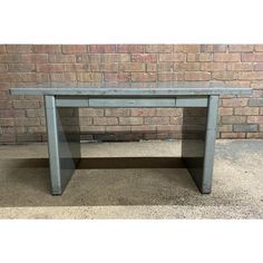 a gray table sitting in front of a brick wall