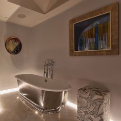 a bathroom with a bathtub, stool and painting on the wall