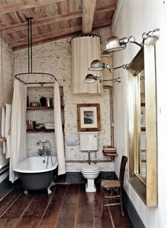 an old fashioned bathroom with wood floors and exposed ceilinging, including a claw foot tub