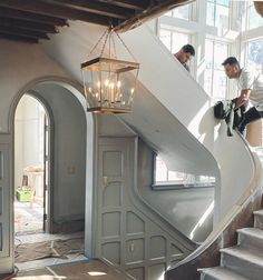 two men are climbing up the stairs in a house that is being renovated with white paint