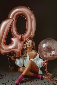 a woman sitting on the ground with balloons and confetti in front of her