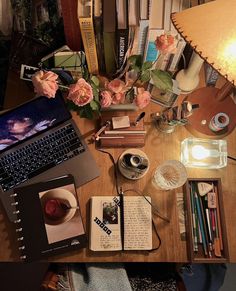 a laptop computer sitting on top of a wooden desk next to a lamp and books