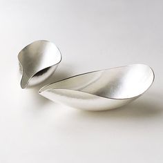 two silver spoons sitting next to each other on a white surface