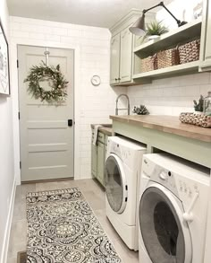 a washer and dryer sitting in a room next to a door with wreaths on it