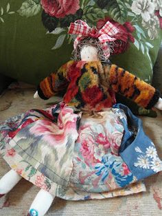 a stuffed animal doll sitting on top of a pillow next to a flowered wall