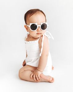 a baby wearing sunglasses sitting on the ground