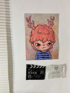 a painting of a boy with red hair and antlers on his head is hanging on the wall