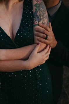 a man and woman embracing each other with tattoos on their arms