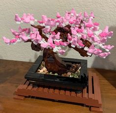 a bonsai tree with pink and white hearts on it's trunk, sitting on a wooden table