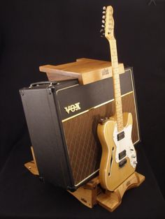 an electric guitar and amp sitting on top of a wooden stand in front of a black background