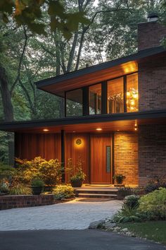 a modern house in the woods with lights on it's windows and steps leading up to