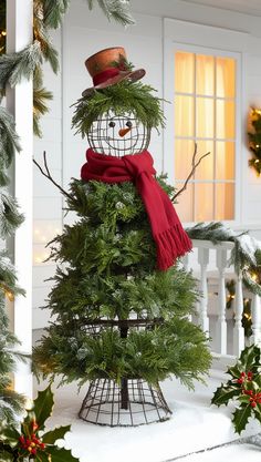 a snowman with a red scarf and hat on top of a small christmas tree