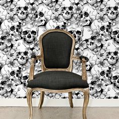 a chair sitting in front of a black and white wallpaper with skulls on it