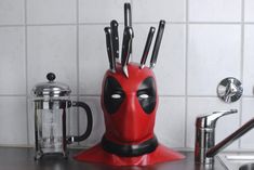 a red deadpool knife holder with knives sticking out of it's centerpiece