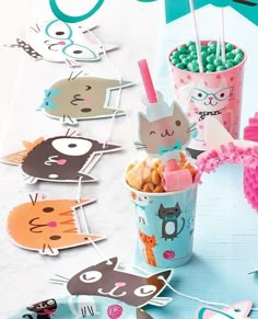 there are many cats on the table with cupcakes and candy sticks in them