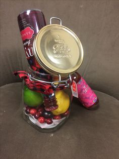 a glass jar filled with assorted fruit and condiments sitting on a couch