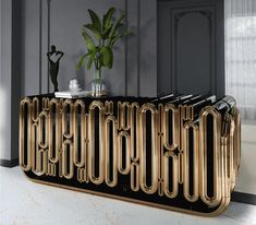 a black and gold console table with a plant on it in front of a gray wall