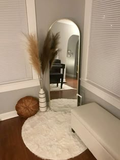 a mirror sitting on top of a wooden floor next to a white bench and ottoman