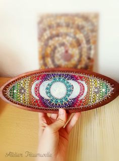 a person holding up a wooden plate with beaded designs on the bottom and sides