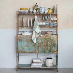 an old metal shelf with dishes on it and a tea towel hanging from the top