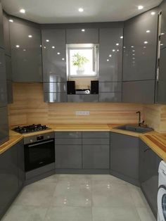 an empty kitchen with grey cabinets and wood counter tops on the walls, along with a washer and dryer