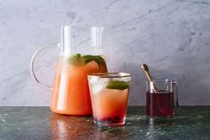 two pitchers and glasses filled with drinks on a table