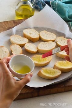 someone is spreading oil on some bread and dipping it in a bowl with a spoon