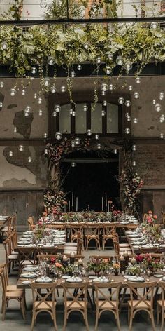 tables and chairs are set up in front of an old building with vines hanging from the ceiling