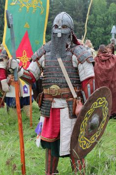 a man dressed in armor and holding two swords standing next to each other on grass