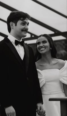 a man in a tuxedo standing next to a woman in a white dress