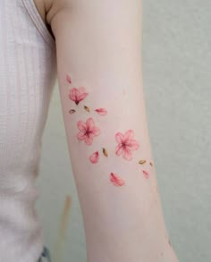 a woman's arm with pink flowers on the left side of her right arm