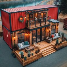 a house made out of shipping containers with lights on the windows and decking area