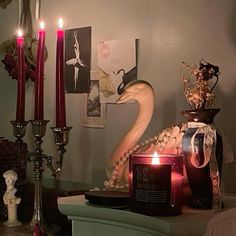 candles are lit on a table in front of pictures and other decorative items, such as an ornament